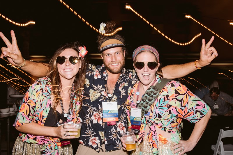 three people smiling at the camera. They are wearing sunglasses and hawaiin shirts.
