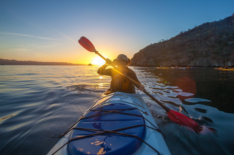 Woman kayaks at sunset- photo by Molly Hagbrand