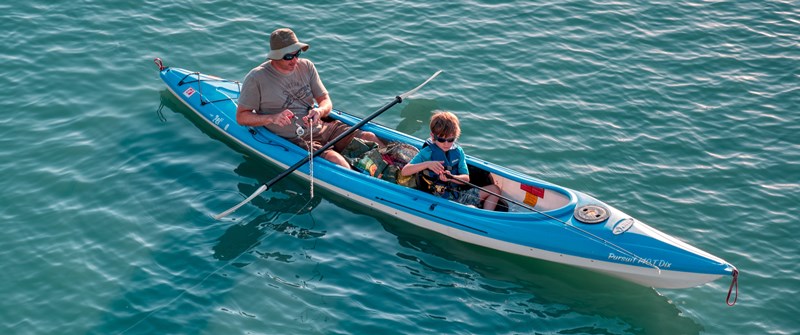 Man and boy fishing in blue kayak