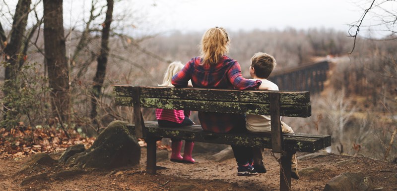 Woman and two children sit admiring outdoor viewpoint