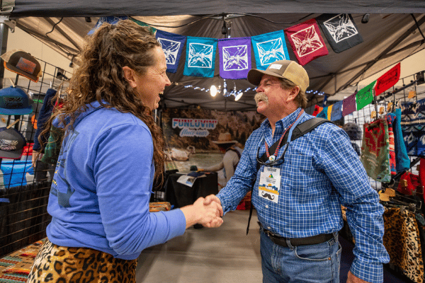 two people shaking hands at an america outdoors member event