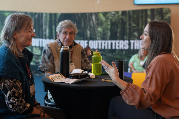 three people having a conversation at an america outdoors conference